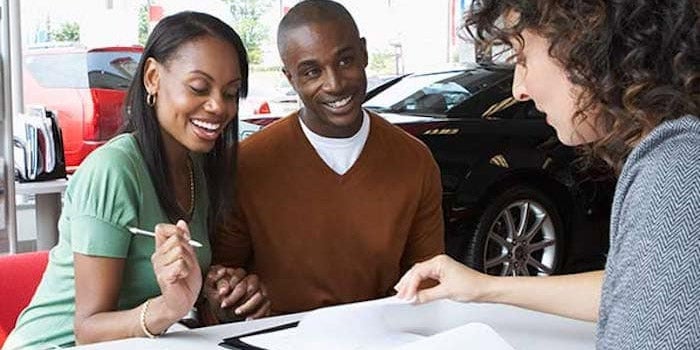 Smiling couple signing lease documents at dealership
